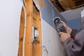 Maintenance repair works of replacement damaged drywall on worker cutting plasterboard with construction electric power