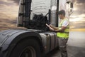 Maintenance and Vehicle inspection. A truck mechanic driver holding clipboard his inspecting safety a large fuel tank of semi truc