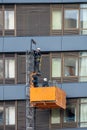 Maintenance workers on a hanging cradle or lifting platform carrying out repair work on the facade of a modern multi-storey office Royalty Free Stock Photo