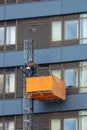 Maintenance workers on a hanging cradle or lifting platform carrying out repair work on the facade of a modern multi-storey office Royalty Free Stock Photo