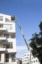 Maintenance workers working at heights from an articulated boom lift, repairing facade of residential building.