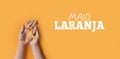 Maio laranja. Hands holding an orange ribbon on an orange background. Concept of protection of children and adolescents