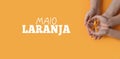 Maio laranja. Hands holding an orange ribbon on an orange background. Concept of protection of children and adolescents