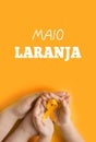 Maio laranja. Hands holding an orange ribbon on an orange background. Concept of protection of children and adolescents