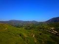 a majestic aerial shot of the lush green hillsides and mountains with a long winding road