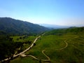 a majestic aerial shot of the lush green hillsides and mountains with a long winding road