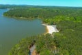 A majestic aerial shot of a rippling lake surrounded by vast miles of lush green trees with a beach on the banks of the lake Royalty Free Stock Photo