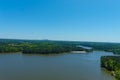 A majestic aerial shot of a rippling lake surrounded by vast miles of lush green trees with a beach on the banks of the lake Royalty Free Stock Photo