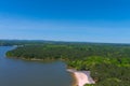 A majestic aerial shot of a rippling lake surrounded by vast miles of lush green trees with a beach on the banks of the lake Royalty Free Stock Photo