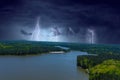 A majestic aerial shot of a rippling lake surrounded by vast miles of lush green trees with a beach on the banks of the lake Royalty Free Stock Photo