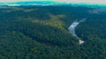 A majestic aerial shot of vast miles of lush green trees with the Chattahoochee river running through them with blue sky and cloud