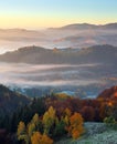 Majestic autumn rural landscape. Interesting sunrise. A view from the lawn to the high mountains and forests in fog. Green meadows