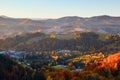 Majestic autumn rural scenery. Landscape with mountains, fields and forests. There are trees on the lawn full of orange leaves.