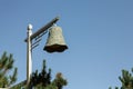 Majestic bell hanging atop a tall wooden pole under a blue sky