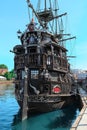 Majestic Black Pirate Ship Moored in Bustling Harbor with City Skyline View Royalty Free Stock Photo