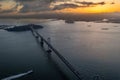 a large bridge crosses the ocean at sunset, with lots of boats Royalty Free Stock Photo