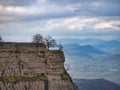 Majestic cliff with trees overlooking a valley - A dramatic view from a rugged cliff with trees, overlooking a serene valley and Royalty Free Stock Photo