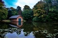 Early autumn view of a wooden cabin by reflective pond water with lily pads in Burger Park, Germany Royalty Free Stock Photo