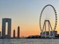 Majestic ferris wheel situated in front of the modern skyline at sunset, creating a memorable scene