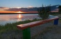 Majestic golden dawn with a contour of trees and an old wooden bench on the river bank Royalty Free Stock Photo