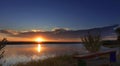 Majestic golden dawn with a contour of trees and an old wooden bench on the river bank Royalty Free Stock Photo