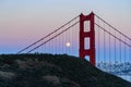 The majestic Golden Gate Bridge, rolling green hills, pink blue sky and the June 2022 full moon alongside the north tower. Royalty Free Stock Photo