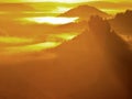 Majestic golden sunrise in a beautiful mountain. Sandstone rock increased from gold foggy valley background.
