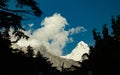 Majestic himalayan mountain Mt sudarshan covered in snow. silhouetted tree line in foreground. blue sky and drifting clouds