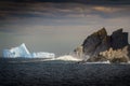 Majestic iceberg seen in calm waters off of a rugged rocky cliff face Royalty Free Stock Photo