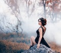 The majestic lady, the dark queen, sits on the stone baring her leg. The brunette girl in the gothic crown. The Royalty Free Stock Photo