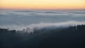 Majestic landscape image of cloud inversion at sunset over Dartmoor National Park in Engand with cloud rolling through forest on