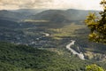 Majestic mountain landscape with green valley, river, village, lush green forest on ridges of slopes in summer sunny day with gold