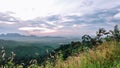 Majestic mountain peak illuminated by a vibrant sunset over rolling hills and lush greenery Royalty Free Stock Photo