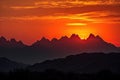 majestic mountain range, with fiery sunset in the background and silhouettes of peaks in view Royalty Free Stock Photo