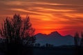 majestic mountain range, with fiery sunset in the background, and silhouettes of trees against the sky Royalty Free Stock Photo