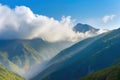 majestic mountain range, with misty clouds and sunshine, against blue sky Royalty Free Stock Photo