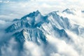 majestic mountain range rises above a sea of clouds, its peaks adorned with intricate patterns of snow and ice Royalty Free Stock Photo