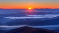 Majestic mountain sunrise paints clouds and fog in orange sky, creating stunning landscape view