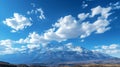 Majestic mountains capped with snow, under a clear blue sky with soft, white clouds. Royalty Free Stock Photo