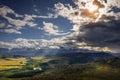 Majestic panorama of mountain plain on the background of snow-covered ridge before thunderstorm. Sun`s rays break through huge