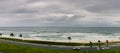 Majestic Seascape of beach, waves, cars, clouds and cyclist on a cloudy day
