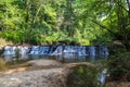 A majestic shot of a waterfall on South Fork Peachtree Creek surrounded by lush green trees reflecting off the water at Lullwater