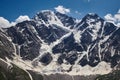 Majestic snow-capped mountains with deep crevasses and glaciers against a blue sky with wispy clouds