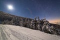 The majestic starry sky over the winter mountain landscape. Night scene. Wonderful tall fir trees with moonlight Royalty Free Stock Photo