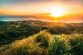 Majestic sunrise over the hills and ocean below, with lush green grass in the foreground, Guam