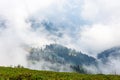 Majestic view on beautiful fog mountains in mist landscape. Alpine meadows in the foreground. In the distance the top of a Royalty Free Stock Photo