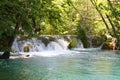 A majestic view of the turquoise water and the sun`s rays in the Plitvice Lakes National Park. Croatia. Europe. A small waterfall