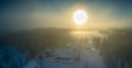 Majestic view of winter sunset with very large sun spot in frozen foggy air, winter pine tree forest, aerial, Grano village,