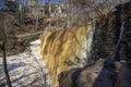 a majestic waterfall with bare winter trees, lush green plants and water flowing along Big Creek River at Vickery Creek Falls