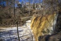 a majestic waterfall with bare winter trees, lush green plants and water flowing along Big Creek River at Vickery Creek Falls